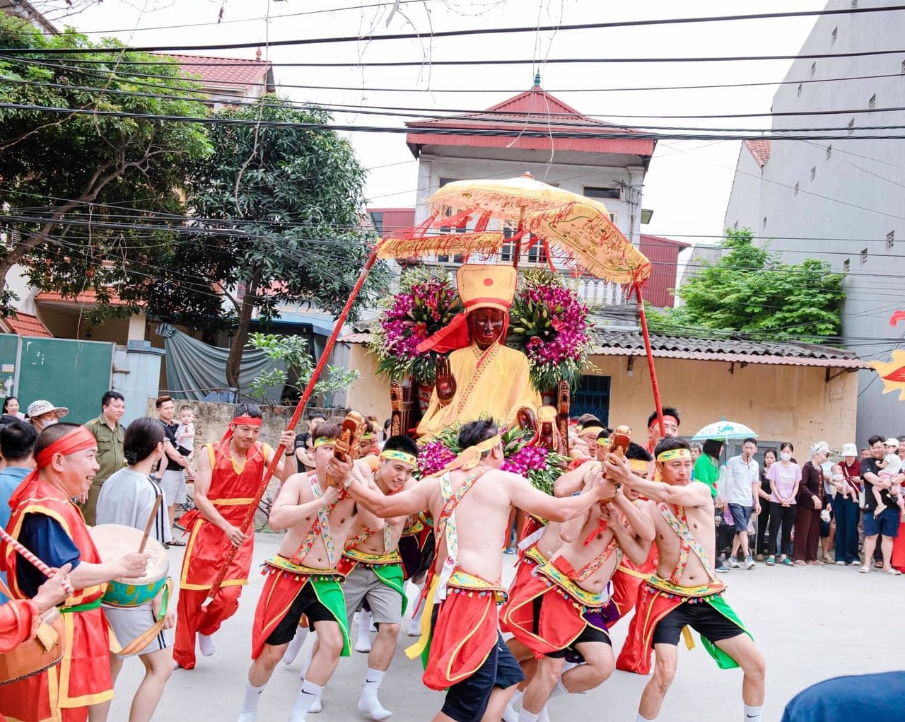Đoàn trai làng cởi trần thắt đai đỏ vàng khiêng kiệu thánh qua đường làng
